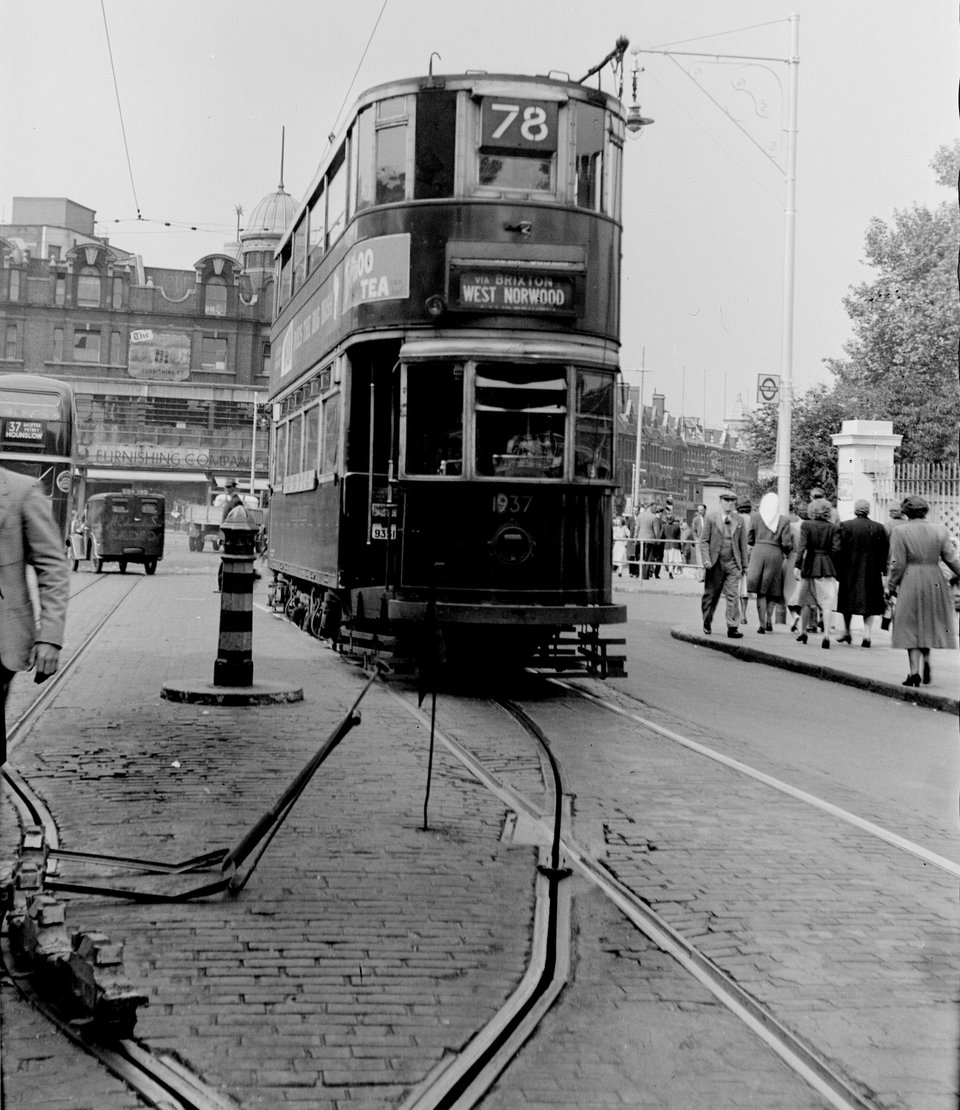 the point at which a tram driver would 'shoot the plough' and raise the trolley pole on leaving a conduit section of track. Tramcar 1937 at Effra Road, Brixton. H.B. Priestley, 21/5/1949.